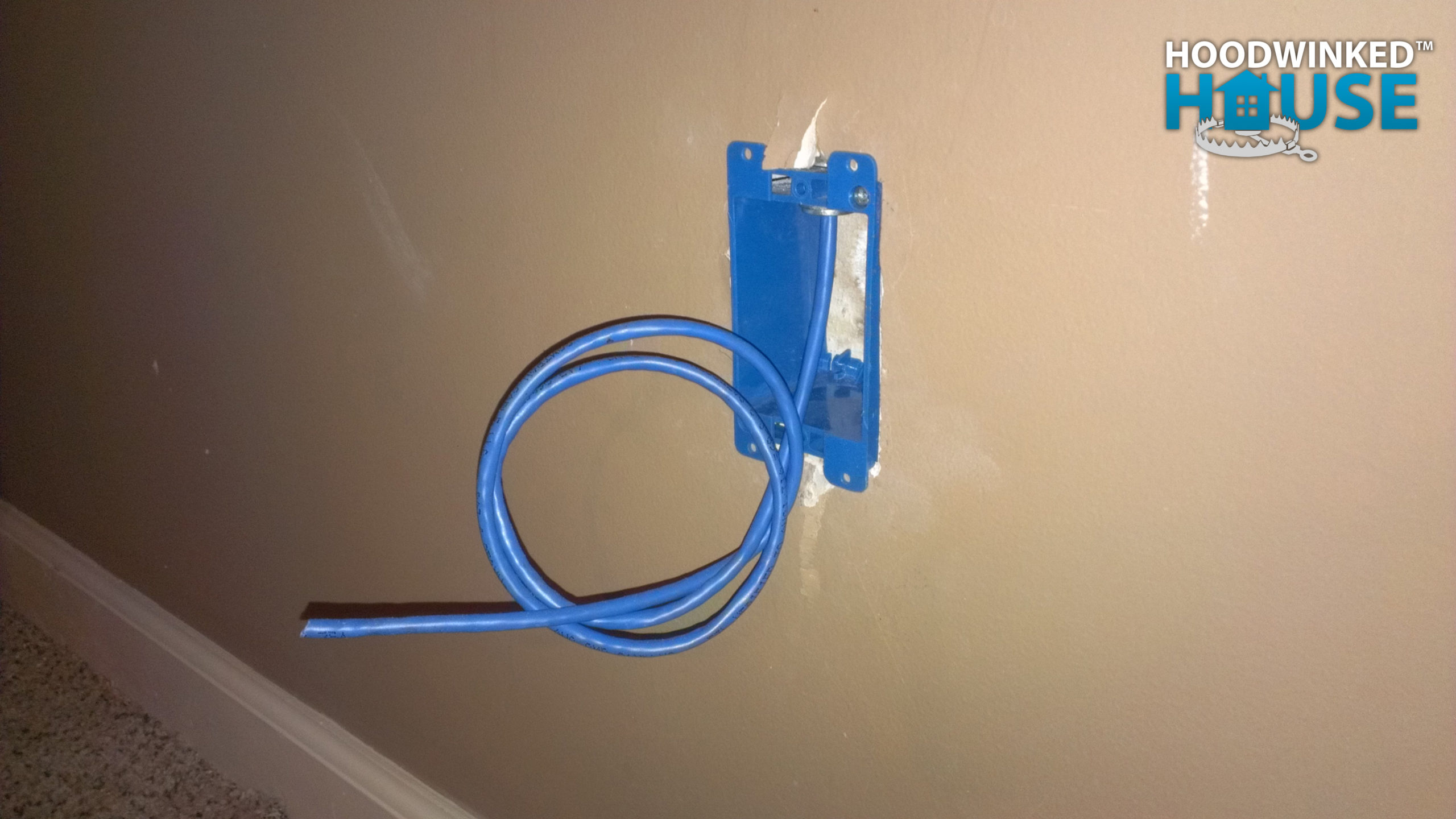 A household network rough in project includes this tail of CAT6 cable emerging from a wall junction box and coiled to keep it off the floor.