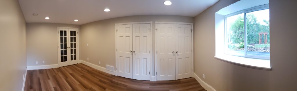 Panoramic view of a bedroom showing double French doors, two closets each with double doors, and an egress window.