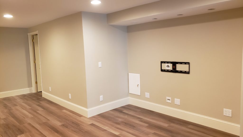 And empty family room with a TV mount and structured media panel. The rest of the room is empty.