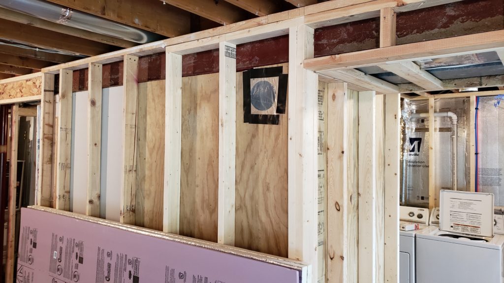 A cold air return between studs is temporarily covered to keep dust out.